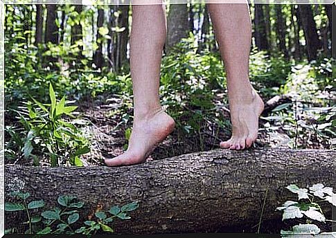 Woman walks barefoot on a log being happier