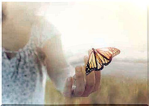 Woman holding a butterfly in her hand.