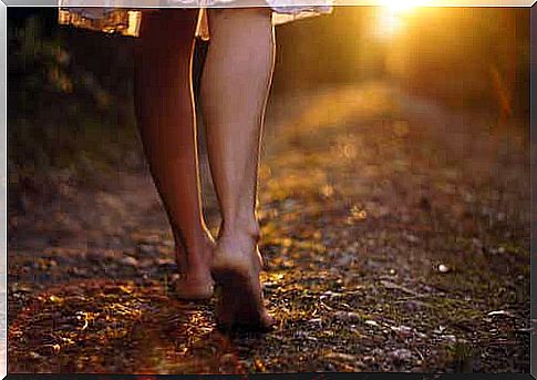 Woman walking barefoot along a country path.