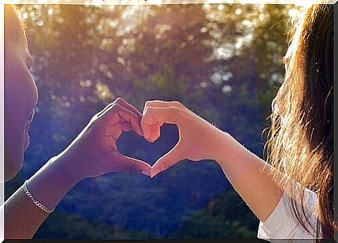 Two girlfriends form a heart with their hands