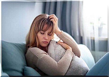 Sad woman sitting on the sofa with closed eyes.