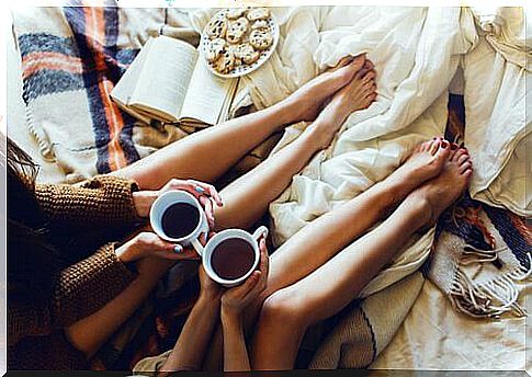 friends drink herbal tea on the bed